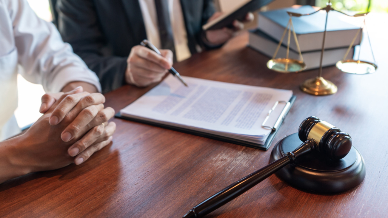 Lawyer working with client discussing contract papers with brass scale about legal legislation in courtroom, consulting to help their customer.